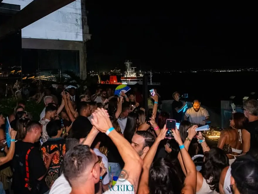 Pista lotada do Vórtice no D-Edge, à beira da baía, com o público de braços erguidos